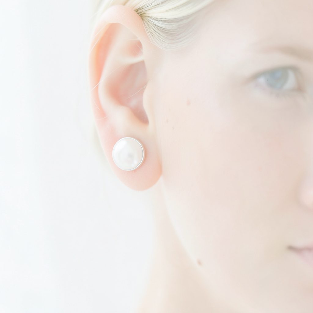 Photographie douce de boucles d'oreilles en corail sur fond clair, ambiance minérale et lumineuse