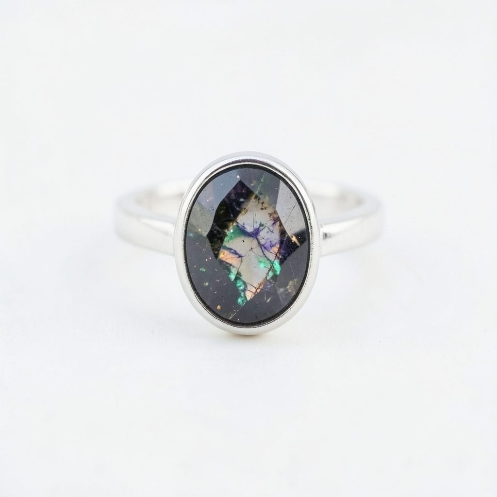 Vue rapprochée d'une bague en argent rhodié ornée d'un cabochon de labradorite aux volumes généreux, sur fond beige clair