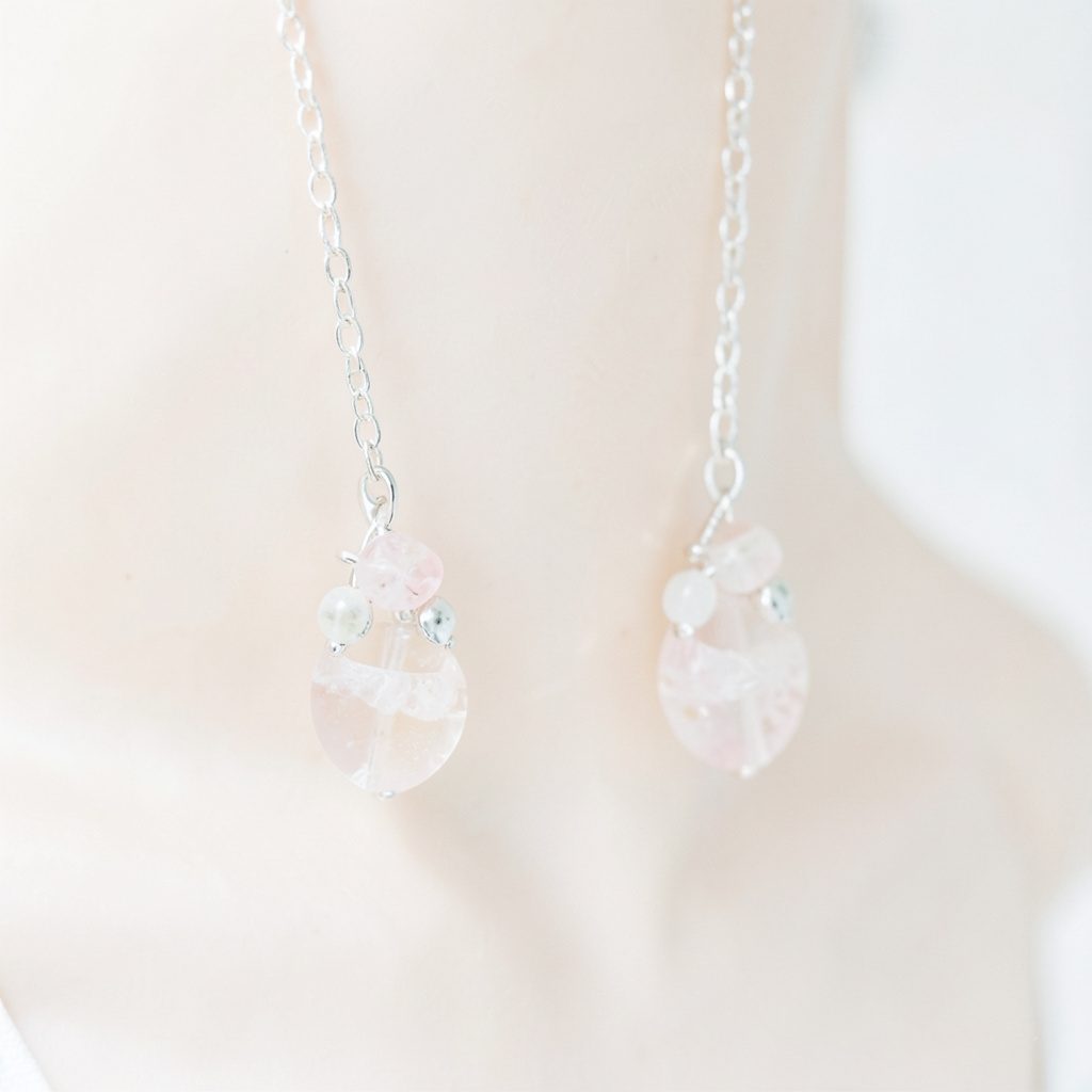Pendants d'oreilles en corail suspendus à une chaîne d'argent, ambiance minérale aux teintes blush et crème